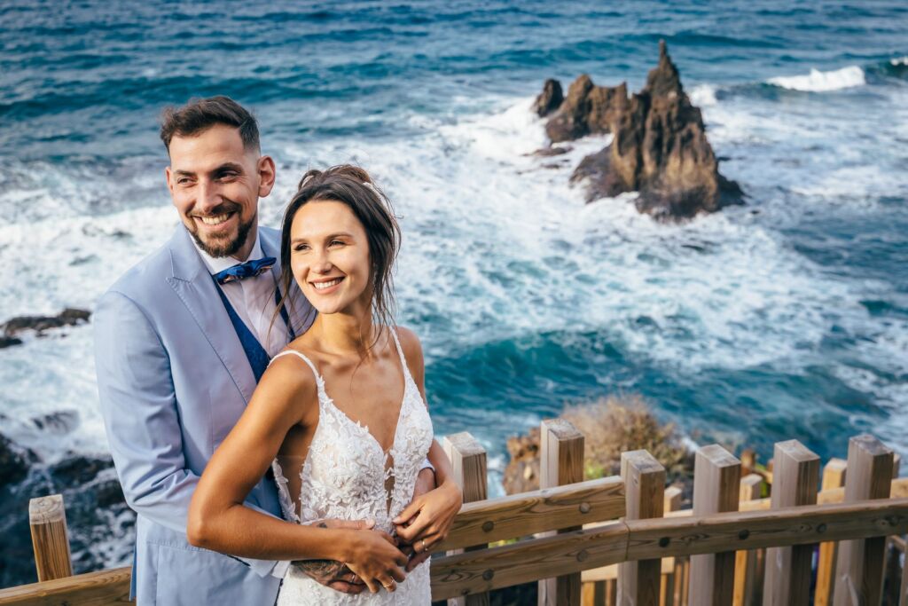 Postboda en Tenerife: Irina y David en Almáciga 3 Postboda en Tenerife: David abrazando a Irina por la cintura junto a la barandilla de madera