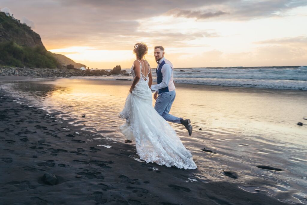 Postboda en Tenerife: Irina y David en Almáciga 15 Postboda en Tenerife: Irina y David corriendo de la mano por la arena negra con el vestido ondeando