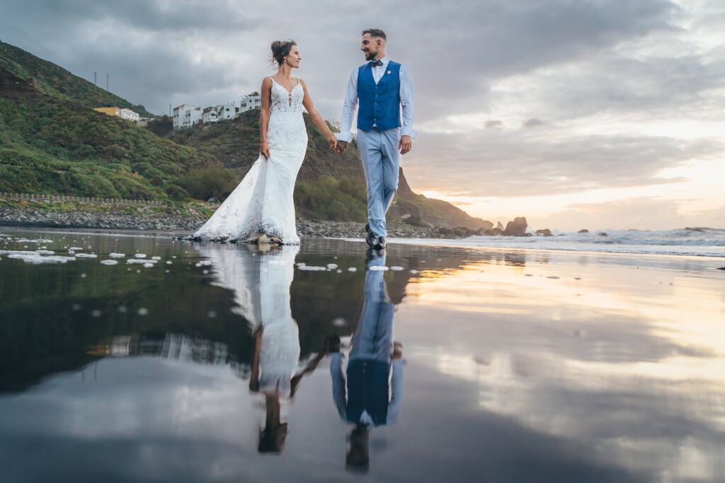 Postboda en Tenerife: Irina y David en Almáciga 11 Postboda en Tenerife: Irina y David caminando hacia cámara por la arena húmeda con reflejo
