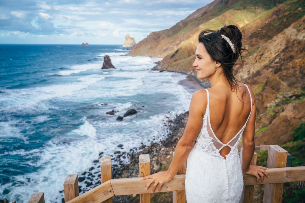 Postboda en Tenerife: Irina y David en Almáciga 2 Postboda en Tenerife: Irina apoyada en la barandilla de madera mirando al mar y los acantilados