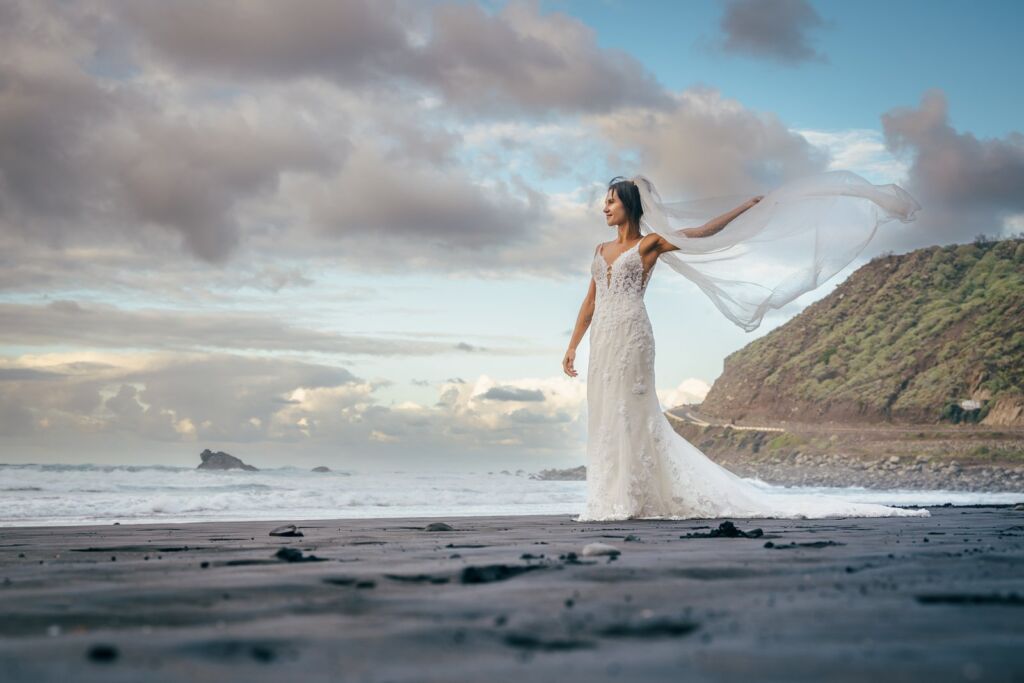 Postboda en Tenerife: Irina y David en Almáciga 21 Postboda en Tenerife: Irina sola en la arena negra con el velo volando en horizontal por el viento