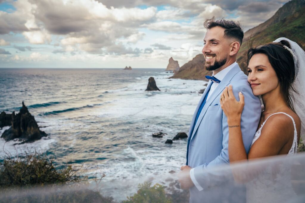 Postboda en Tenerife: Irina y David en Almáciga 22 Postboda en Tenerife: Irina y David sonriendo a cámara con el mar y la roca al fondo