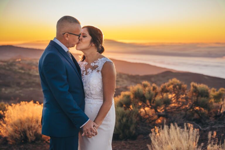 Cómo trabajo: fotógrafo bodas en Tenerife 20 Pareja de novios besándose sobre el mar de nubes al atardecer, entre la vegetación de alta montaña de Tenerife, durante su sesión de postboda