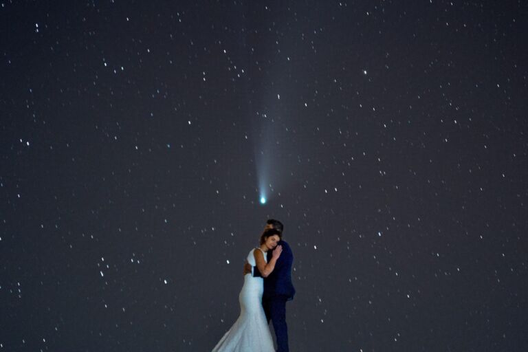 Cómo trabajo: fotógrafo bodas en Tenerife 32 Pareja de novios abrazándose de noche bajo un cometa visible en el cielo estrellado, durante su sesión de postboda en Tenerife